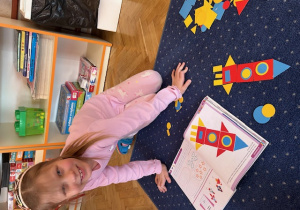 Dziewczynka układa na dywanie rakietę