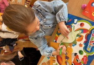 Dziewczynka koloruje dinozaura