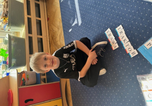 Chłopiec układa wyrazy wskazane przez nauczyciela