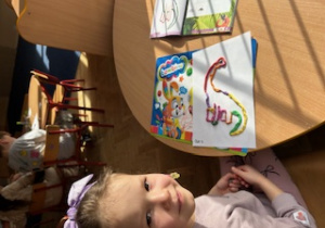 Dziewczynka ze swoją pracą plastyczną pozuje do zdjęcia