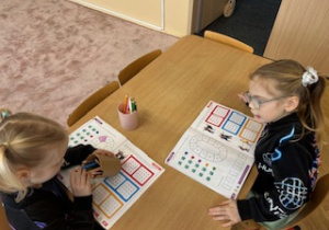 Dziewczynki wykonują polecenia w kartach pracy