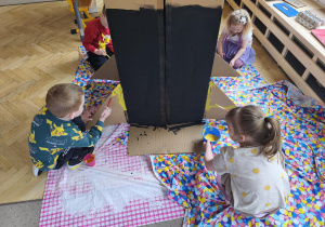 Dzieci mulują farbą duży karton