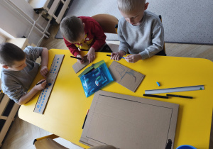 Chłopcy rysują na kartonie pulpit sterujący rakiety