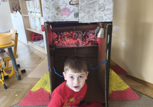 Chłopiec siedzi przed rakietą wykonaną wspólnie przez grupę