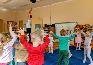 Dzieci stoją w kole z rękami w górze