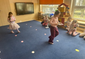 Dziewczynki niosąc talerzyki z piłkami pokonują jajeczny slalom