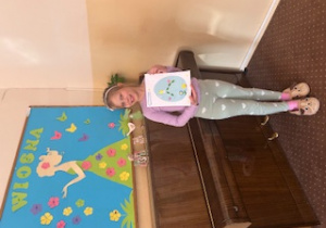 Dziewczynka pozuje do zdjęcia ze swoją własnoręcznie wykonaną pracą plastyczną