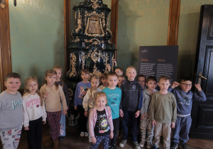 Zdjęcie grupy przed zabytkowym piecem w muzeum