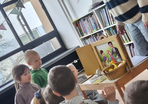 Grupa dzieci siedzi przed teatrzykiem