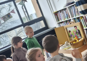 Dzieci siedzą przed teatrzykiem