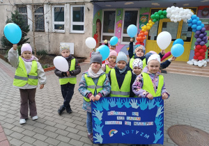 Dzieci stojące z plakatem i balonami