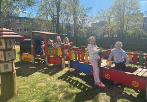 Dziewczynki bawią się na przedszkolnej lokomotywie z wagonikami