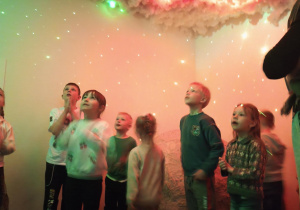 Dzieci patrzą na różowo zielono białą chmurę na suficie