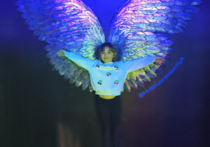 Dziewczynka na tle świetlnych, błękitnych skrzydeł