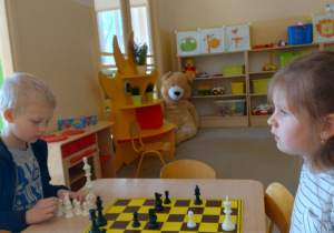 Chłopiec ustawia białe pionki