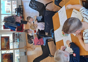 Dzieci siedzą przy stolikach