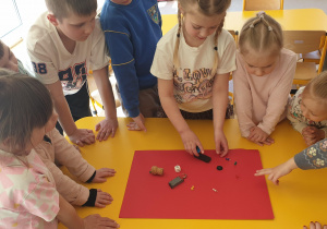 Grupa dzieci przy stoliku sprawdza, jakiego rodzaju materiały przyciąga magnes