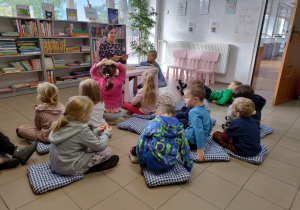 dzieci słuchają bajki czytanej przez panią bibliotekarkę