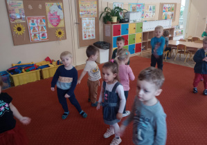 Dzieci na dywanie tańczą w rytm muzyki.