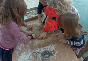 Dzieci wykrawają kształty z ciasta.