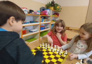 Chłopiec trzyma dłoń nad szachownicą.