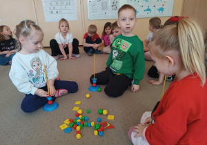 Dzieci siedzą na dywanie z klockami