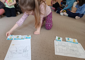 Dziewczynka kładzie obrazek na dywanie