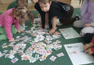 Dzieci patrzą na obrazki na dywanie